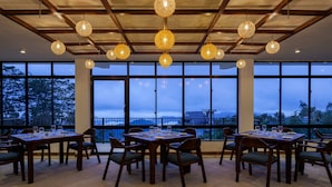 A dining area with tables set for four, large windows, and hanging spherical light fixtures.