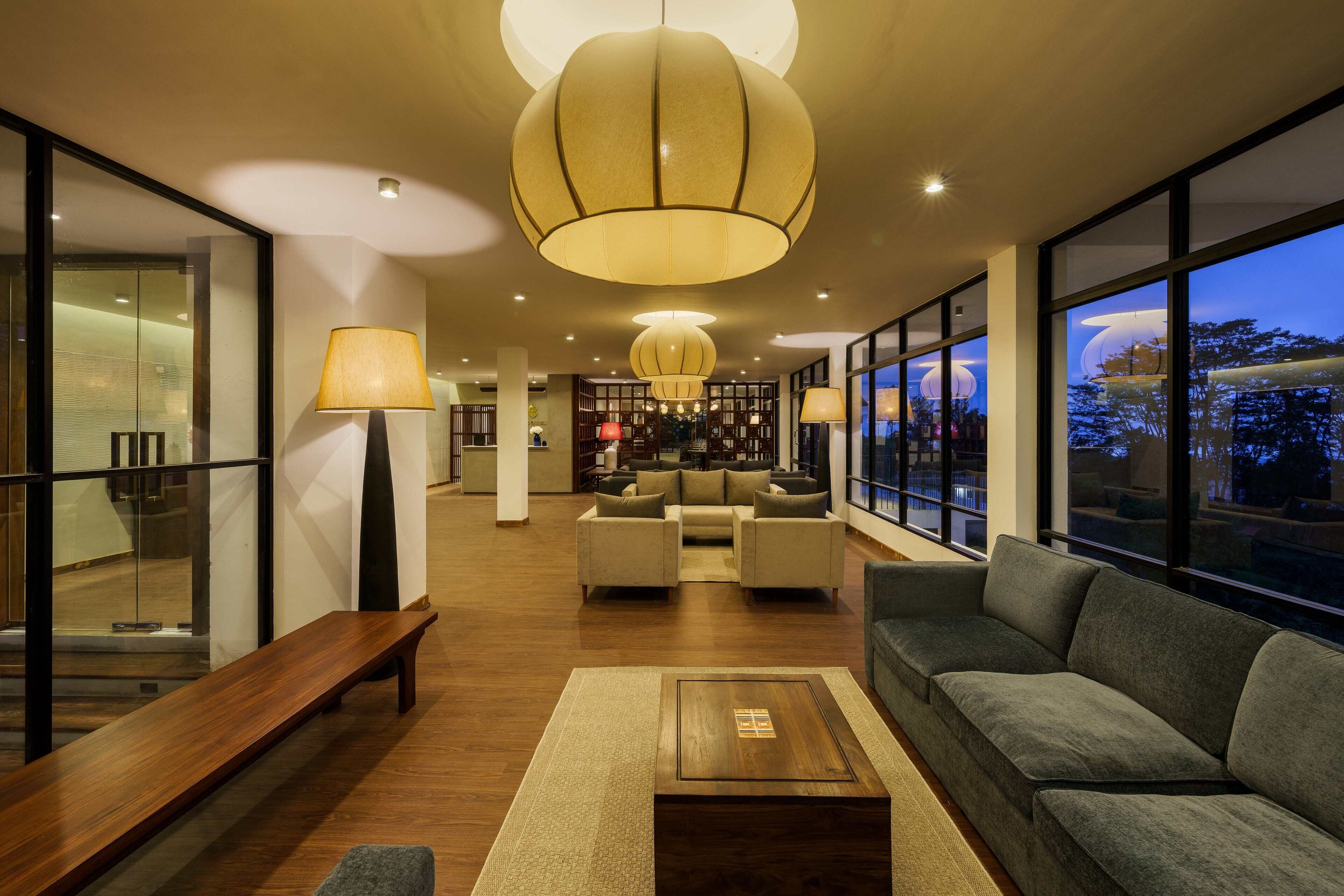 A modern hotel lobby with a wooden bench, sofas, and a coffee table. There are large windows and a view of the outside.