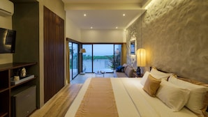 A modern hotel room with a large bed, a television, a desk, and a view of the outdoors.