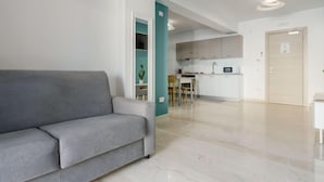 A modern living room with a grey sofa, a teal accent wall, and a kitchen in the background. - Sicilia by Interhome (Balestrate)