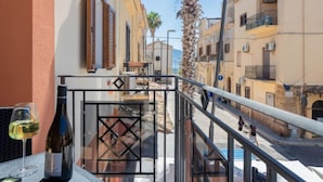 A balcony with a glass railing, a bottle of wine, and a glass on a table. - Sicilia by Interhome (Balestrate)