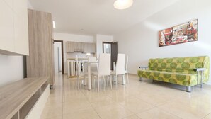Ein modernes Wohnzimmer mit Essbereich, einer Couch und einer Küche im Hintergrund.