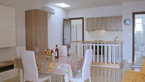 Une cuisine moderne avec des meubles blancs, une table à manger avec des chaises et un petit coin bar.