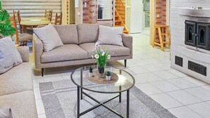 A cozy living room with a sofa, coffee table, and a fireplace. There is a dining area with a table and chairs in the background. - Ilotupa by Interhome (Pertunmaa)