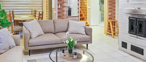A cozy living room with a sofa, coffee table, and a fireplace. There is a dining area with a table and chairs in the background.