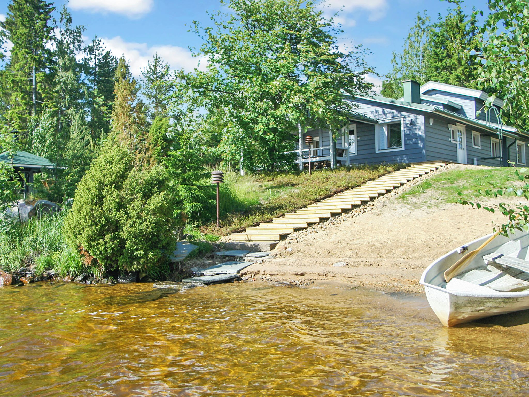Ein Haus mit Anlegesteg und Boot, umgeben von Bäumen und einem klaren Bach.