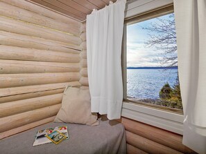 A log cabin room with a window overlooking a body of water.