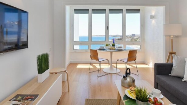 A modern living room with a dining area, large windows with a view, a flat-screen TV, and a sofa. - Apartment Balcon by Interhome (San Agustín)