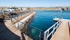 A wooden pier with lounge chairs and a lifebuoy, overlooking a marina with boats and a clear blue sky. - Cabosos 4 by Interhome (Maspalomas)