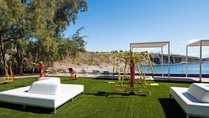 An outdoor area with exercise equipment, white lounge chairs, and a view of the sea. - Cabosos 4 by Interhome (Maspalomas)