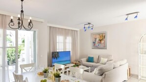 A modern living room with a flat-screen TV, a sofa, a dining table with chairs, and a chandelier. - Cabosos 4 by Interhome (Maspalomas)