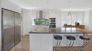 Een moderne keuken met een centraal eiland, roestvrijstalen apparatuur en barkrukken.