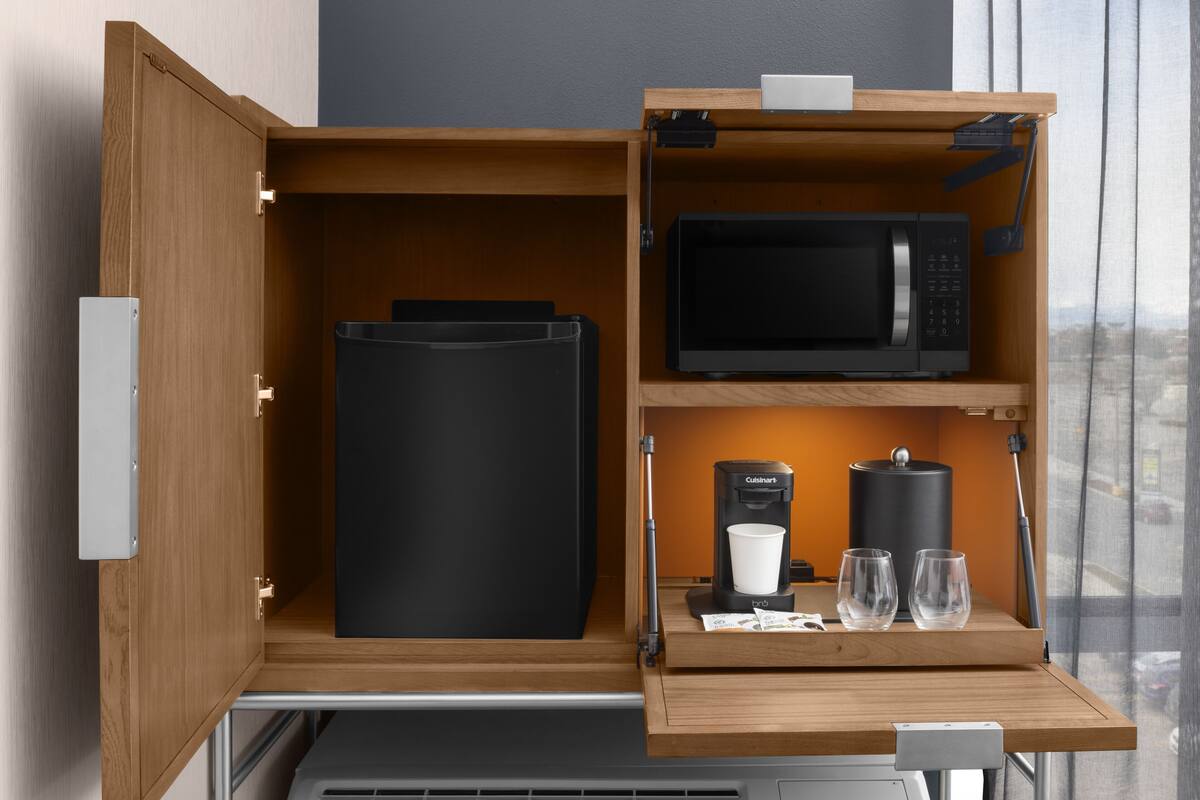 Una cocina compacta equipada con microondas, cafetera y refrigerador pequeño.