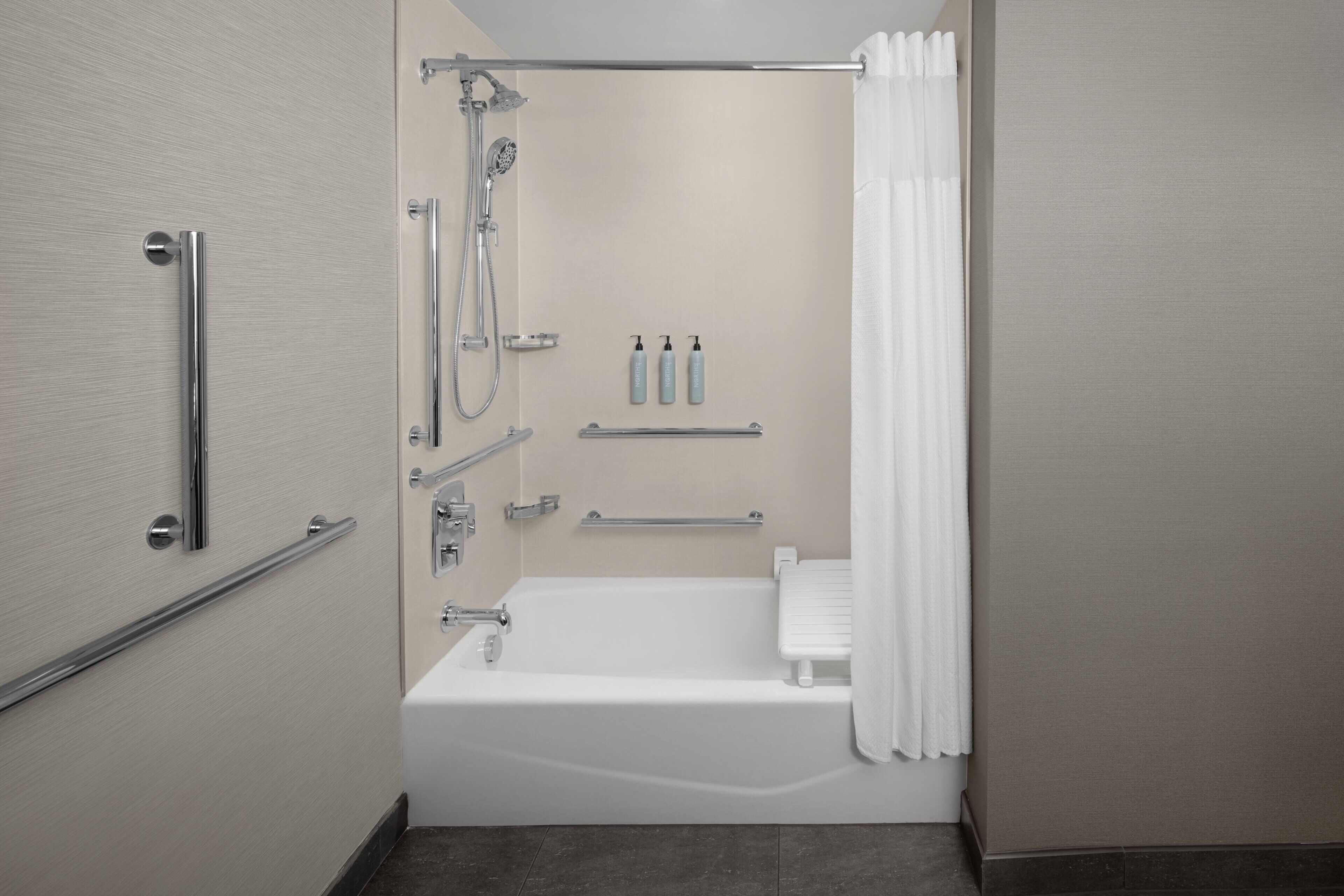 Un baño moderno con bañera, ducha y barras de apoyo.