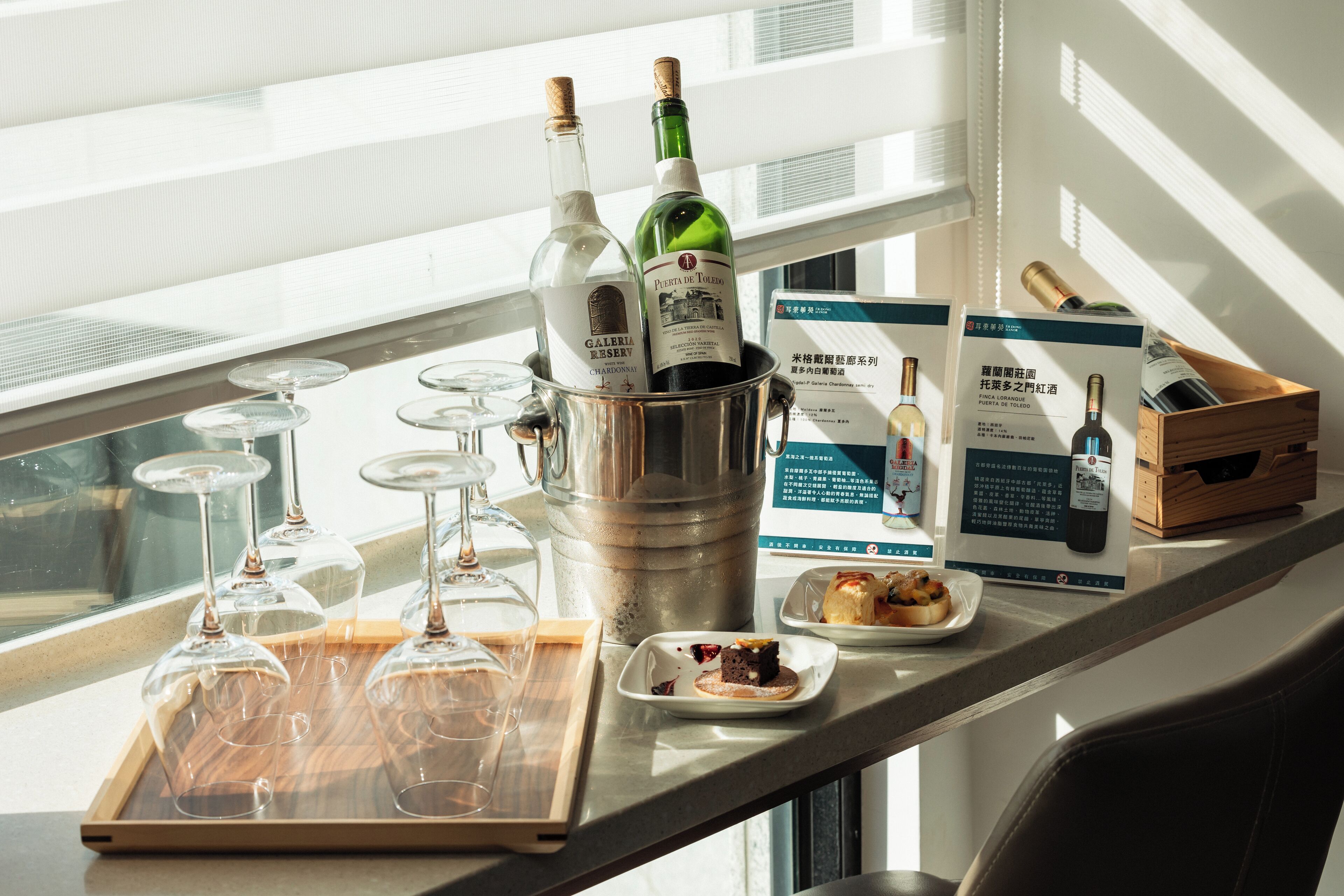A bar area with wine bottles, glasses, and a tray of empty glasses.