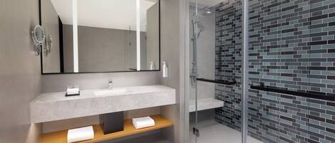 Un baño moderno con cabina de ducha de vidrio, un espejo grande y encimera de mármol.