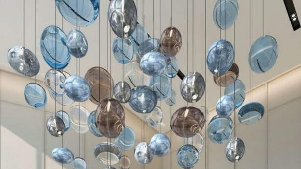 A spacious lobby with a modern design, featuring a large seating area and a unique hanging light installation.