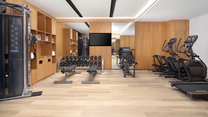 A modern gym with various exercise equipment, including treadmills, dumbbells, and weight machines.