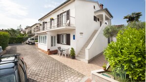 Une maison à deux étages avec un balcon, un escalier et une allée pavée.
