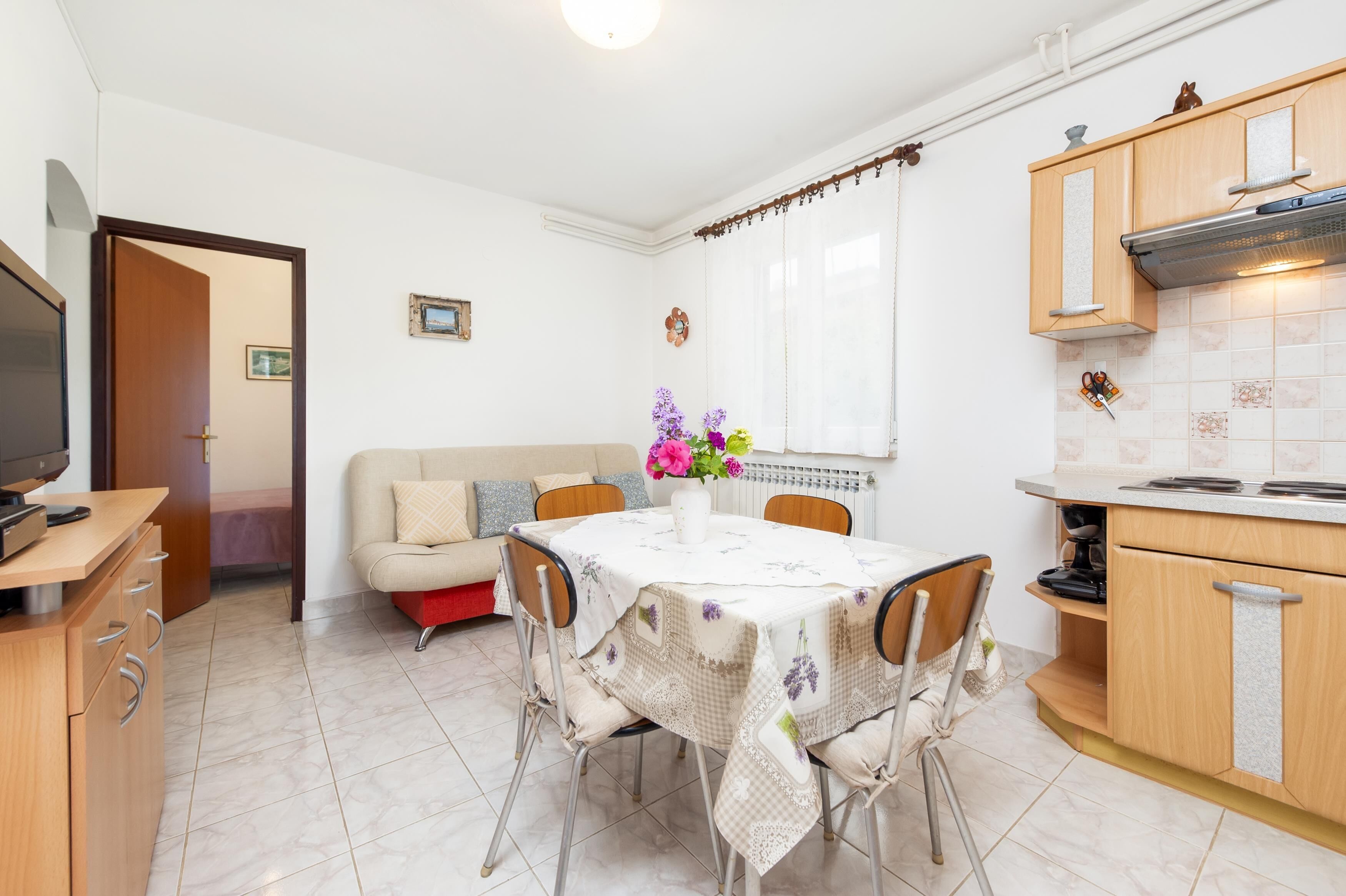 A compact kitchen with a dining table, a sofa, and a TV.