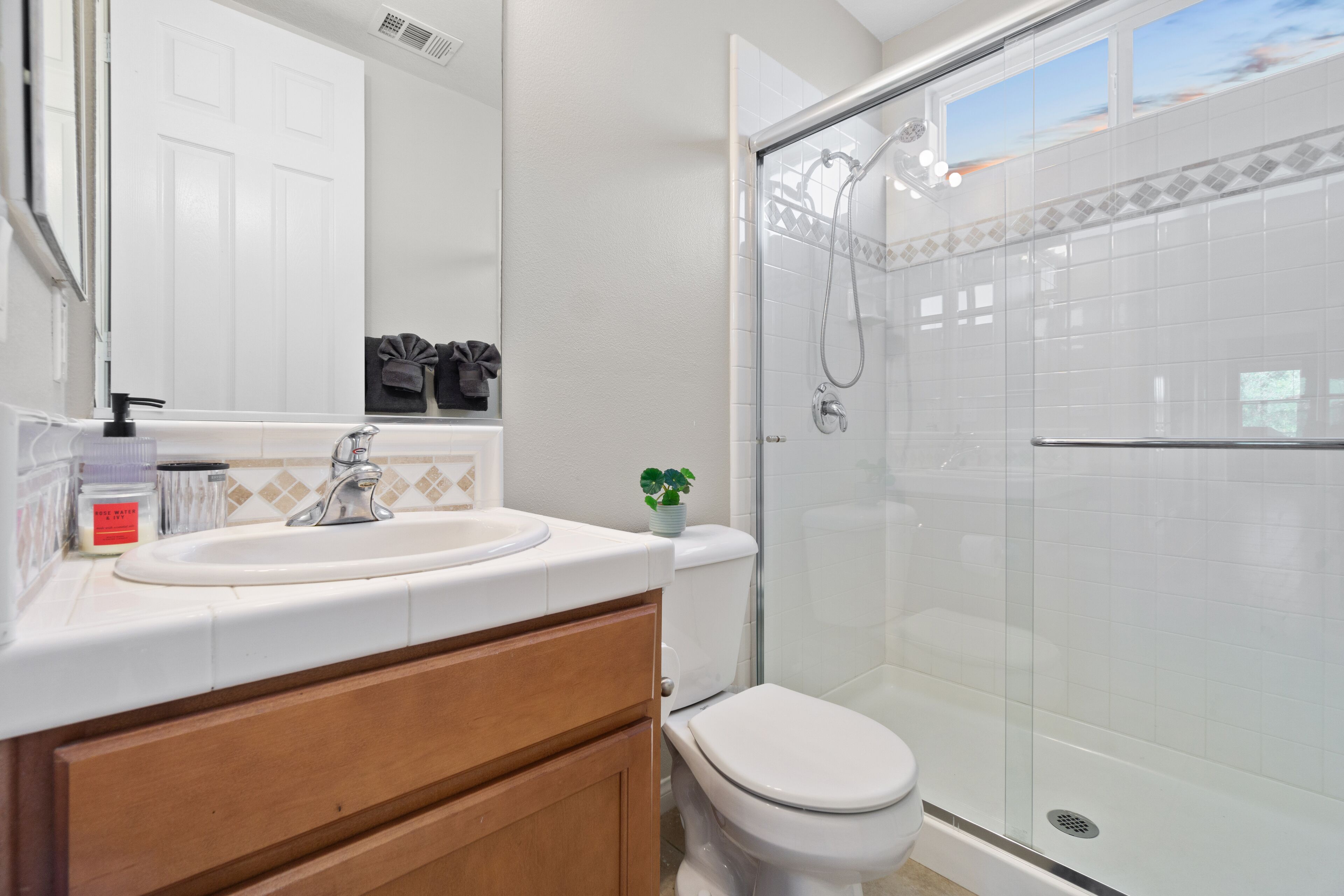 A modern bathroom with a white sink, wooden vanity, and a glass-enclosed shower.