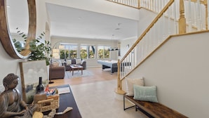 A spacious living area with a wooden staircase, a large mirror, and a Buddha statue. - Resort-style Home with stunning views, pool, hot tub, putting green (Fallbrook)