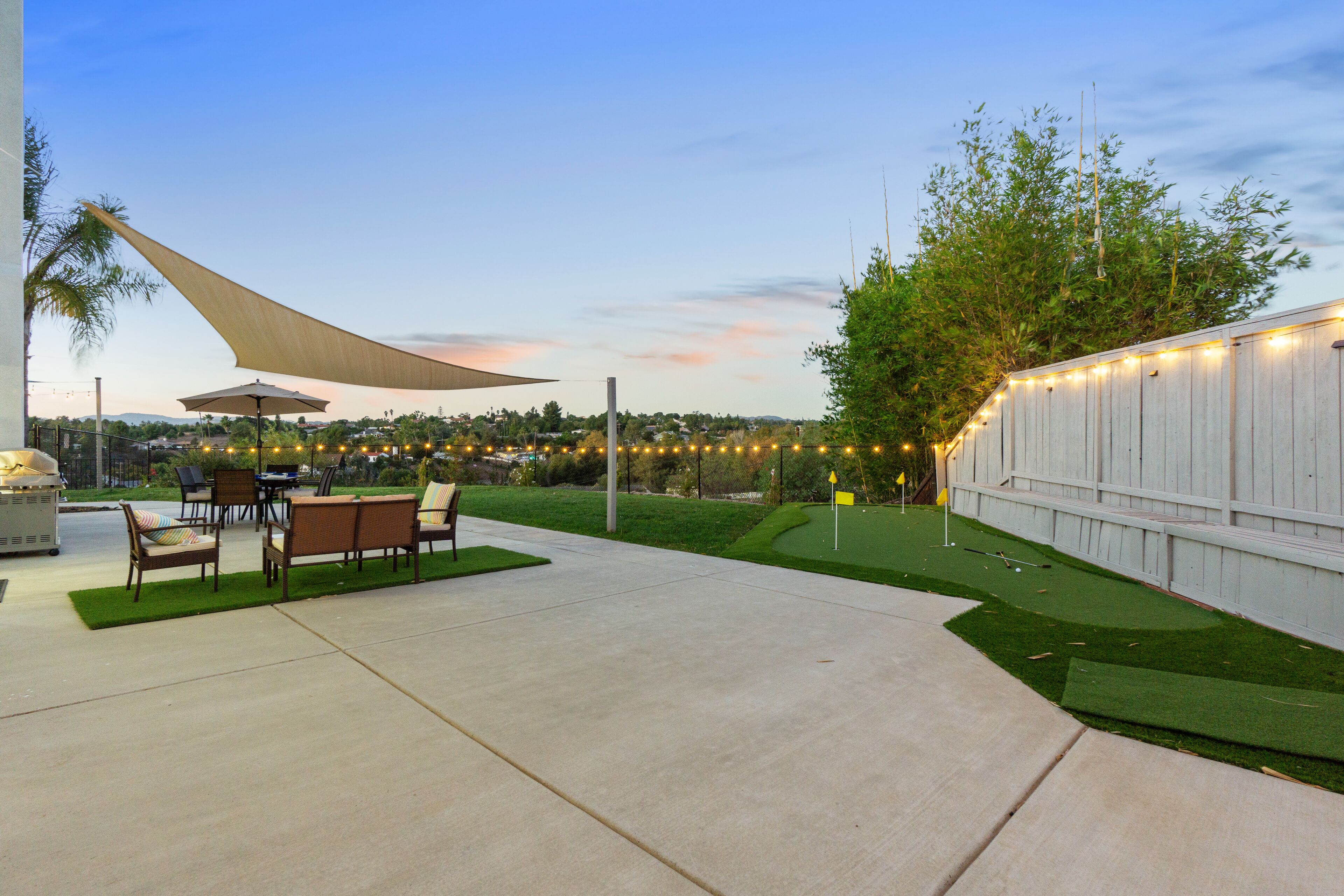An outdoor patio with a dining area, a grill, and a large umbrella.