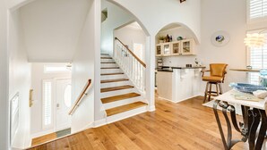 A spacious kitchen with wooden flooring, white cabinetry, and a dining area with a table and chairs.