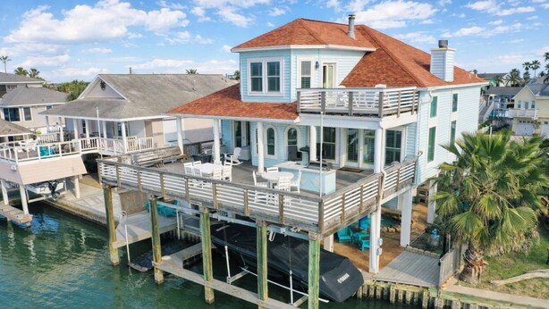 A waterfront house with a balcony, a pool, and a dock.