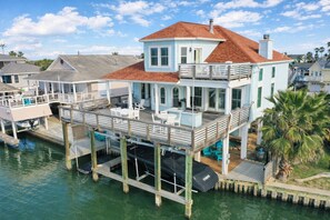 Une maison située au bord de l’eau, dotée d’un balcon, d’une piscine et d’un quai.