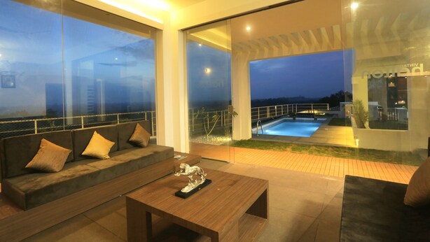 A modern outdoor living area with a sofa, coffee table, and a pool view.