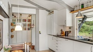 Una cucina moderna con mobili bianchi, un piano di lavoro in legno e una finestra che si affaccia sul verde.