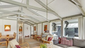 Un'ampia zona giorno con un tavolino in legno, una poltrona e sedie in vimini.