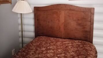 Una cama con una colcha estampada, una lámpara de noche y un cuadro en la pared.