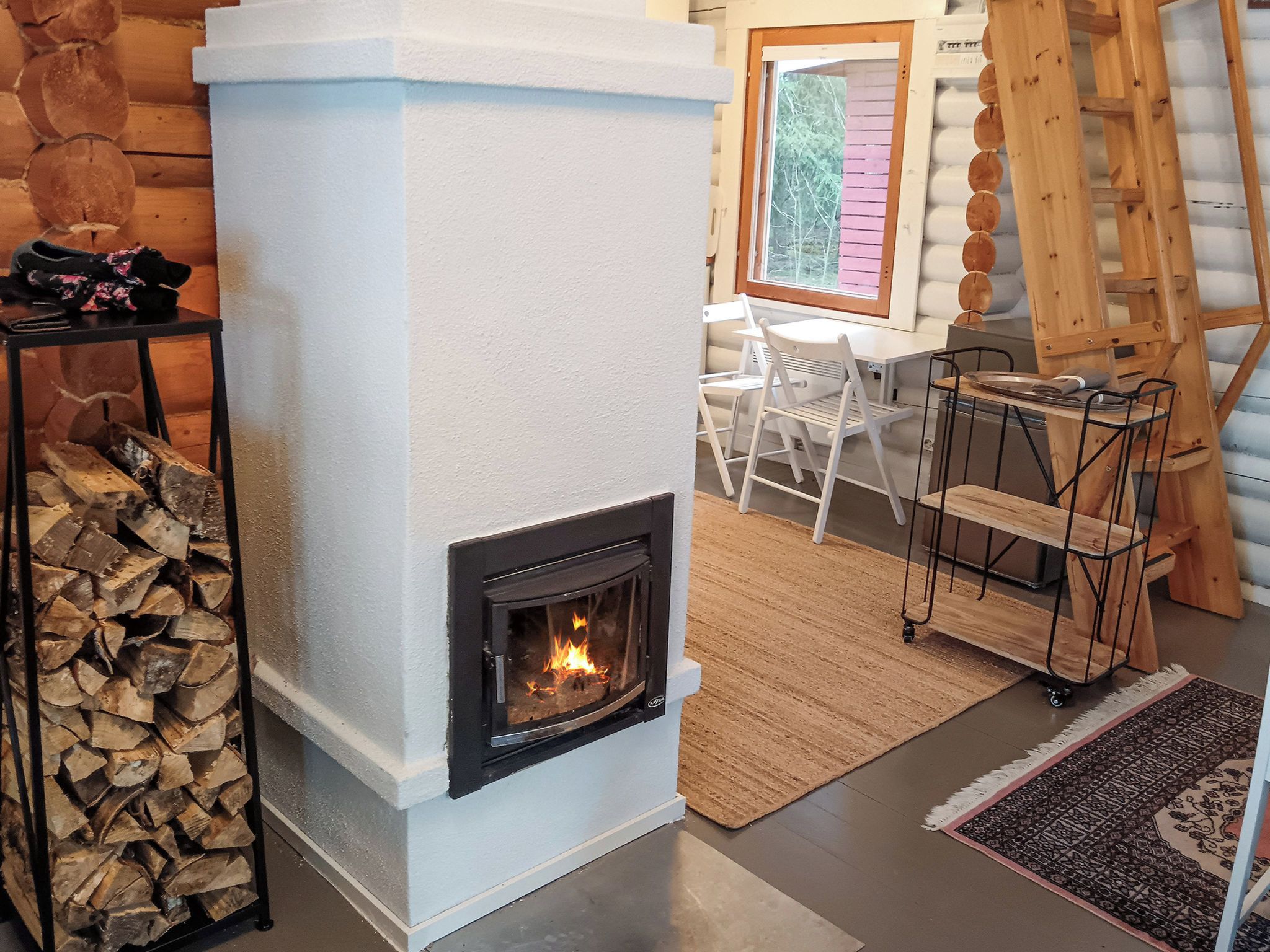 A cozy room with a fireplace, a dining table, and a ladder.