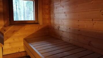 Une pièce de cabane en bois avec un lit simple, une fenêtre et un plancher en bois.