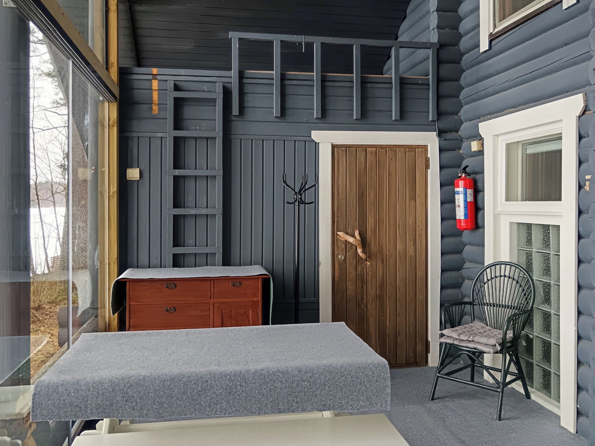 A room with a wooden door, a bench, a chair, and a small table.