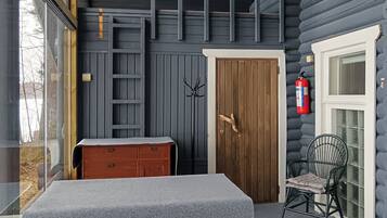 A room with a wooden door, a bench, a chair, and a small table.