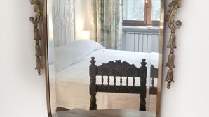 Ein Schlafzimmer mit einem Bett, einem Kopfteil und einem Spiegel mit aufwendiger Goldrahmung.