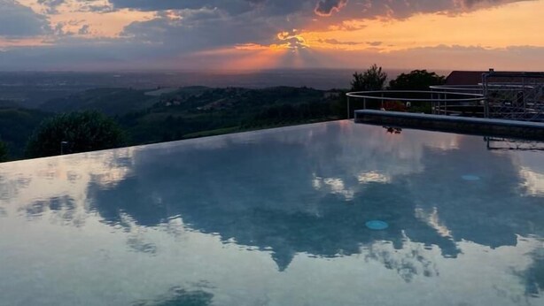 Ein Pool ohne Ende mit freiem Blick auf den Sonnenuntergang und die umliegende Landschaft.
