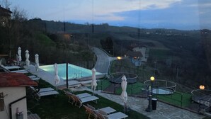 Eine Terrasse mit Liegestühlen, einem Schwimmbad und einer Feuerstelle.
