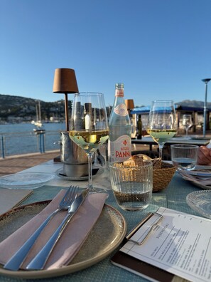 Une table dressée avec des verres à vin, une bouteille d’eau Panna et un menu.