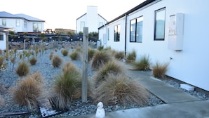 A residential area with modern houses, a gravel pathway, and dry grass landscaping. - Alpine Star - 3 Bedrooms B (Lake Tekapo)