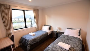 A hotel room with two beds, a desk, and a window with curtains. - Alpine Star - 3 Bedrooms B (Lake Tekapo)