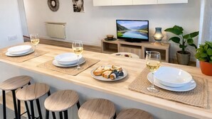 Eine moderne Küche mit Kochinsel, Barhocker, Fernseher und Essbereich.