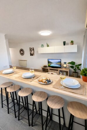Una cucina moderna con isola centrale, sgabelli da bar, televisore e zona pranzo.