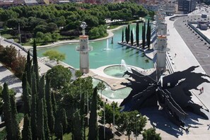 Un parc avec des fontaines, une grande sculpture et de grands arbres.