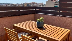 Ein Holztisch mit Stühlen auf einer Dachterrasse mit Blick auf die Stadt.