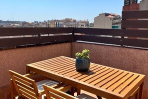 A wooden table and chairs on a rooftop terrace with a city view. - APARTMENTS BCN CENTRAL-ATICO SANTS (Barcelona)