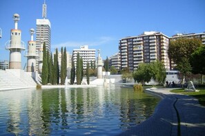 A modern hotel with a central fountain, surrounded by a park with trees and a clear sky. - APARTMENTS BCN CENTRAL-ATICO SANTS (Barcelona)
